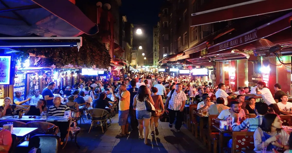Lively street scene in Kadikoy at night, with illuminated restaurants or bars